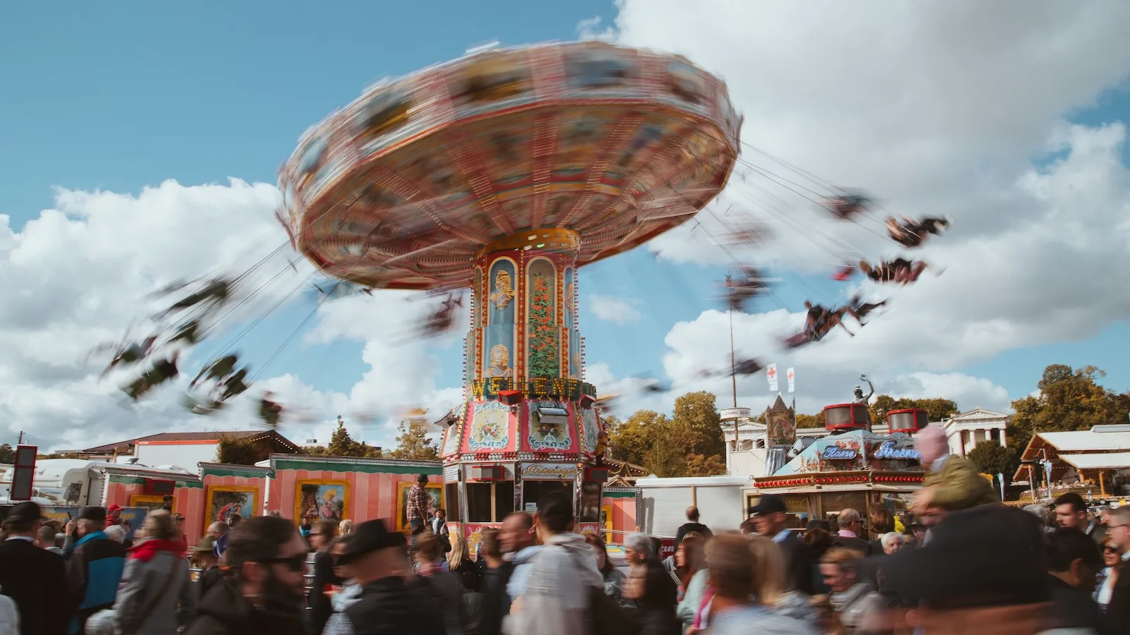 crowds at an amusement park approaching a flying chairs ride